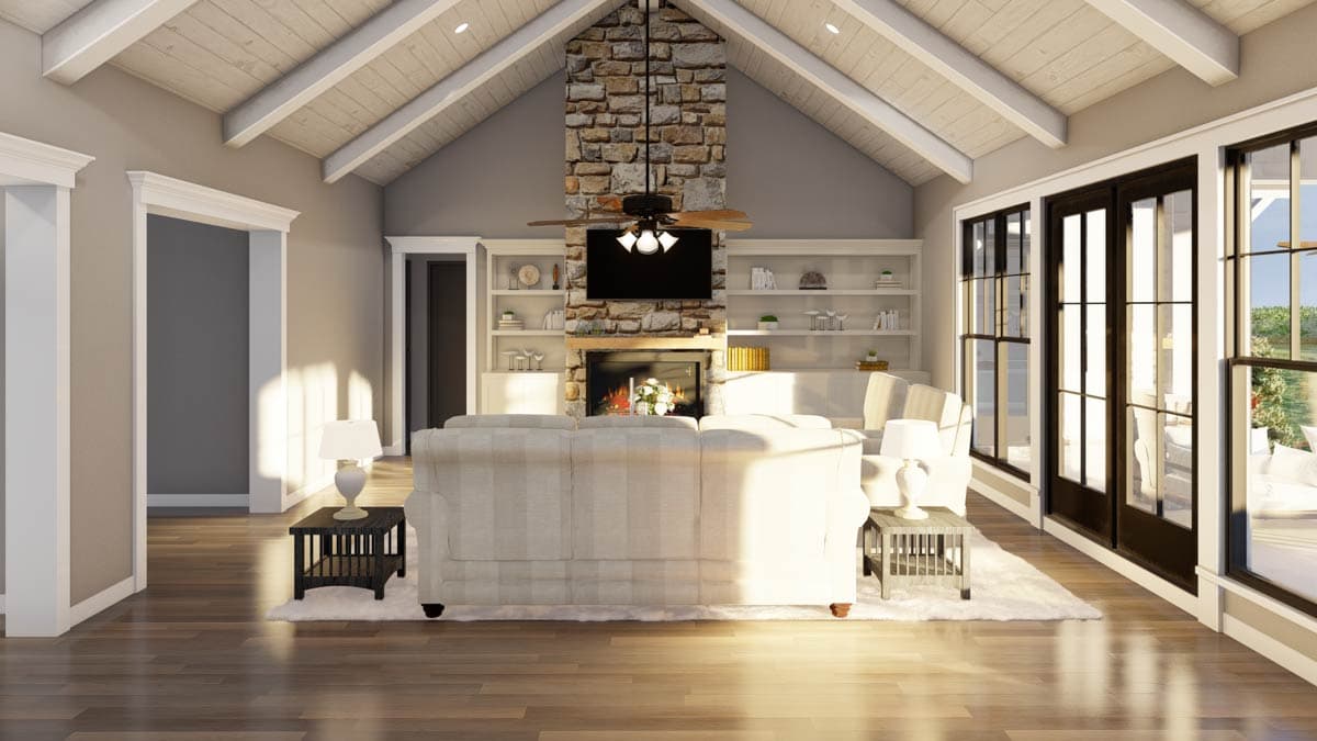 Great room with stone fireplace, vaulted wood-paneled ceiling, built-in shelving, and French doors.
