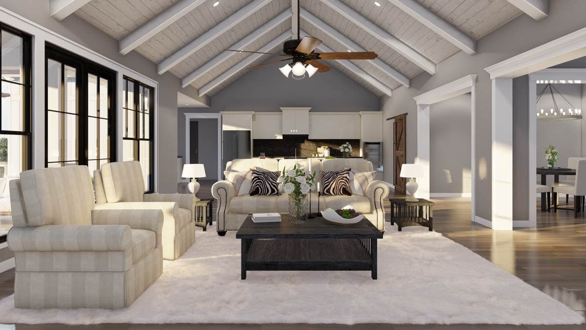 Great room with vaulted beamed ceiling, open to kitchen with island. Large windows, fireplace, and plush rug.