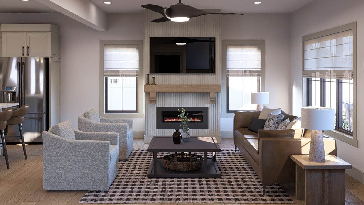 Living room with fireplace, mounted television, leather sofa, two armchairs, and kitchen island with bar stools.