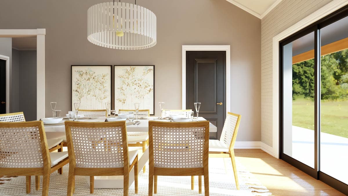 Dining room with wood-framed chairs with cane backs, a large white table, contemporary pendant light, and sliding glass doors.