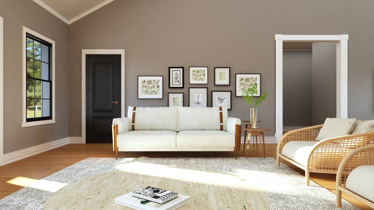 Living room with a white sofa, gallery wall, black door, large window, and rattan chairs. Vaulted ceiling.