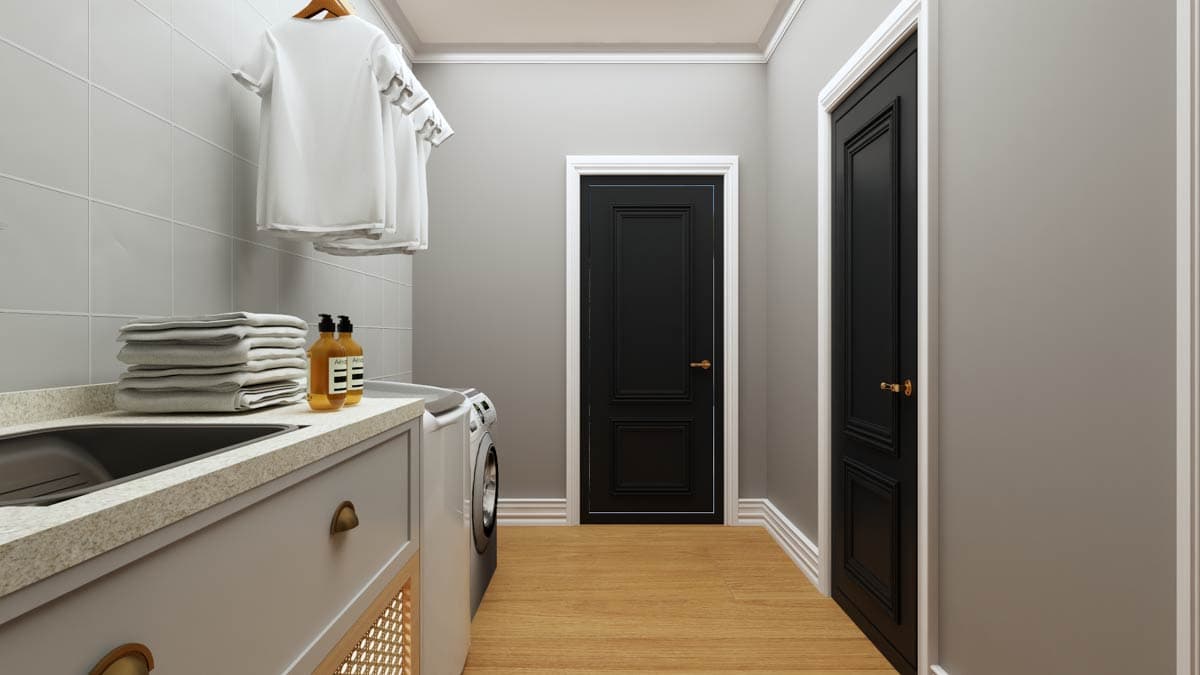 Laundry room with stacked towels, soap dispensers, washing machine, stone countertop, and two black paneled doors.