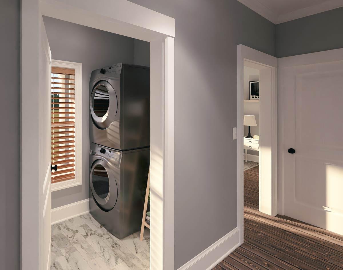 Laundry room with stacked washer/dryer, window with blinds, and marble-patterned floor. Open doorway shows wood floors and another room.