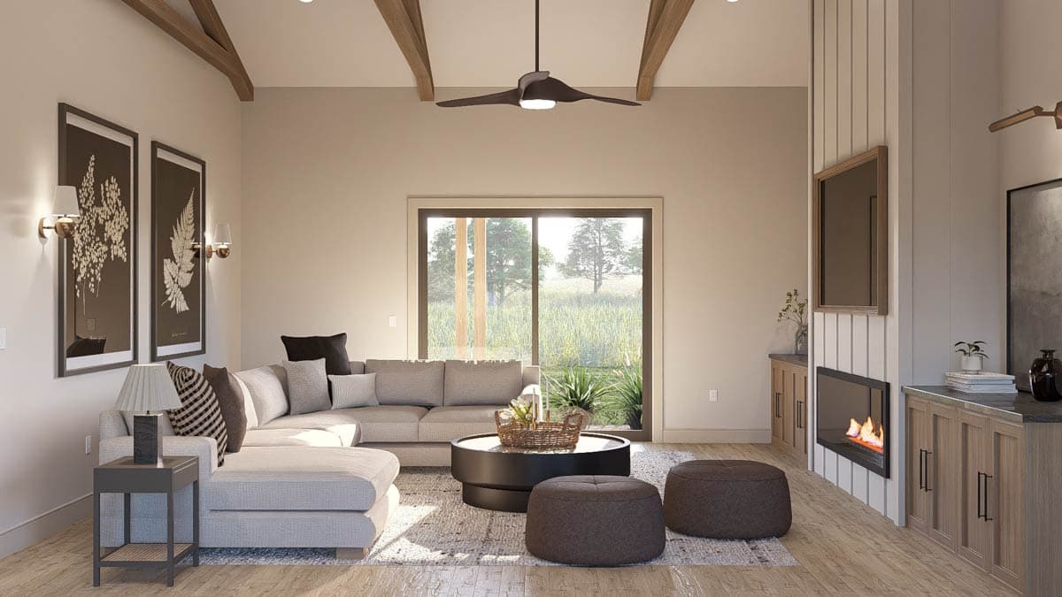 Living room interior with vaulted beamed ceiling, sectional sofa, fireplace, and large window overlooking a field.