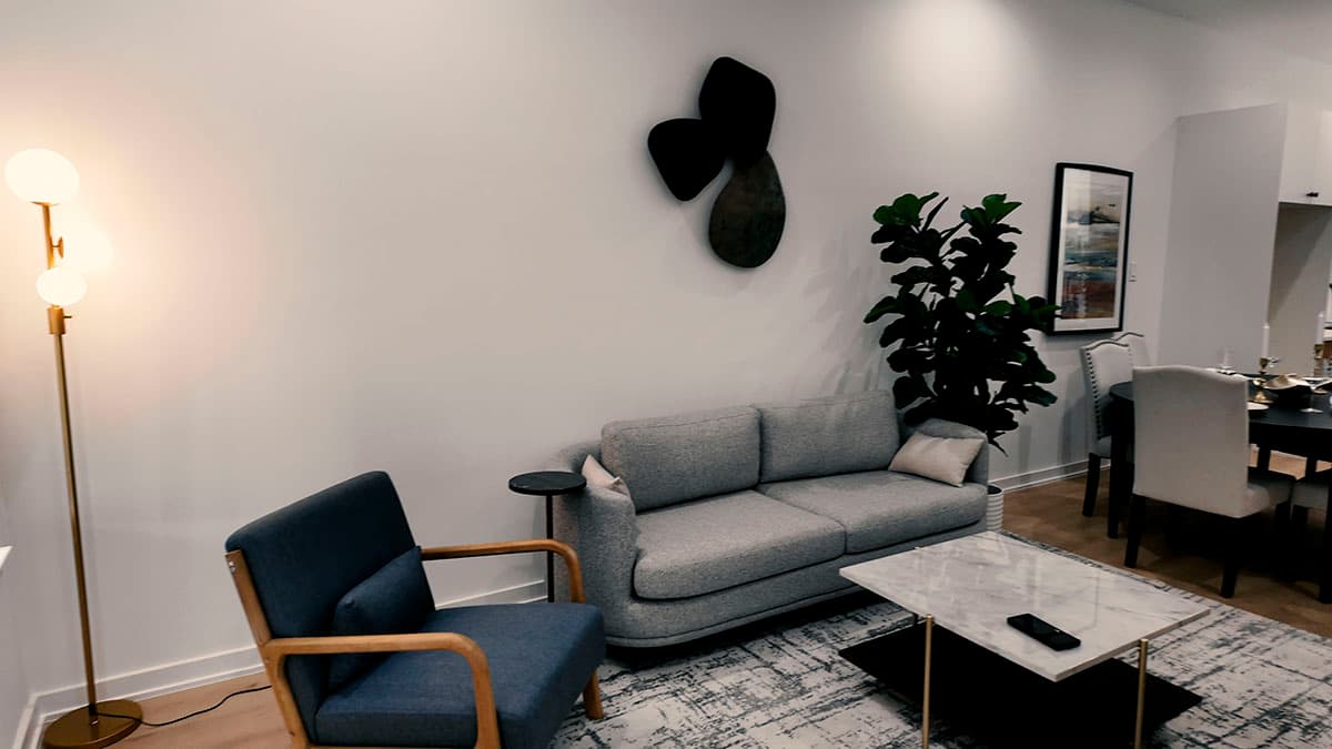 Living room with gray sofa, armchair, marble coffee table, floor lamp, and dining area.