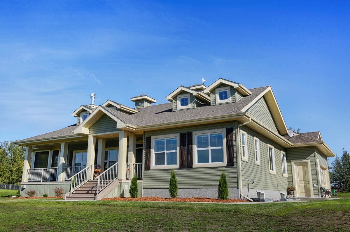 House plan exterior: Two-story house with a covered porch, multiple gables, dormers, and a side-facing garage.