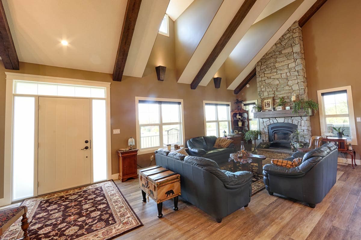 Great room with vaulted beamed ceiling, stone fireplace, and entryway.
