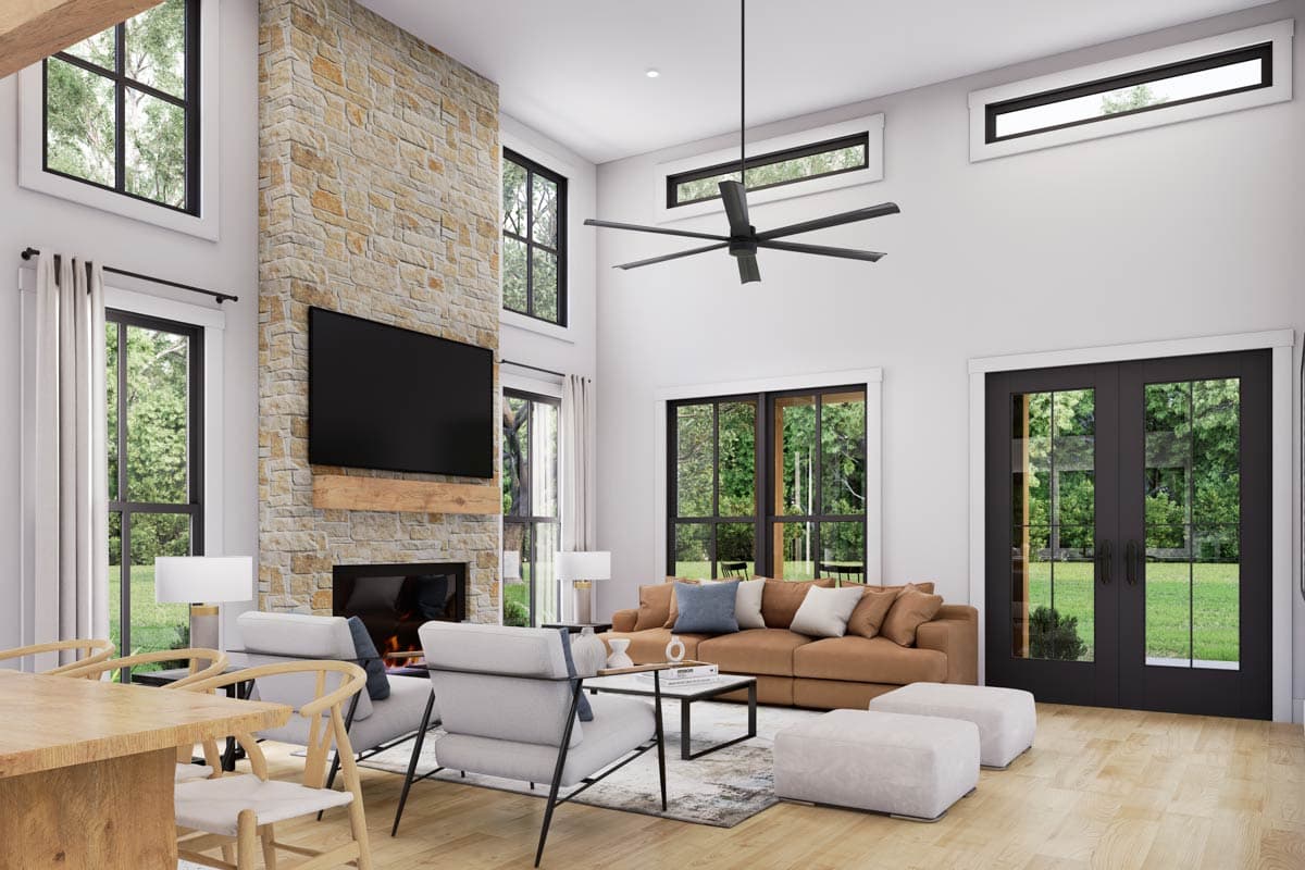 Great room with vaulted ceiling, stone fireplace, large windows, and double doors to exterior.