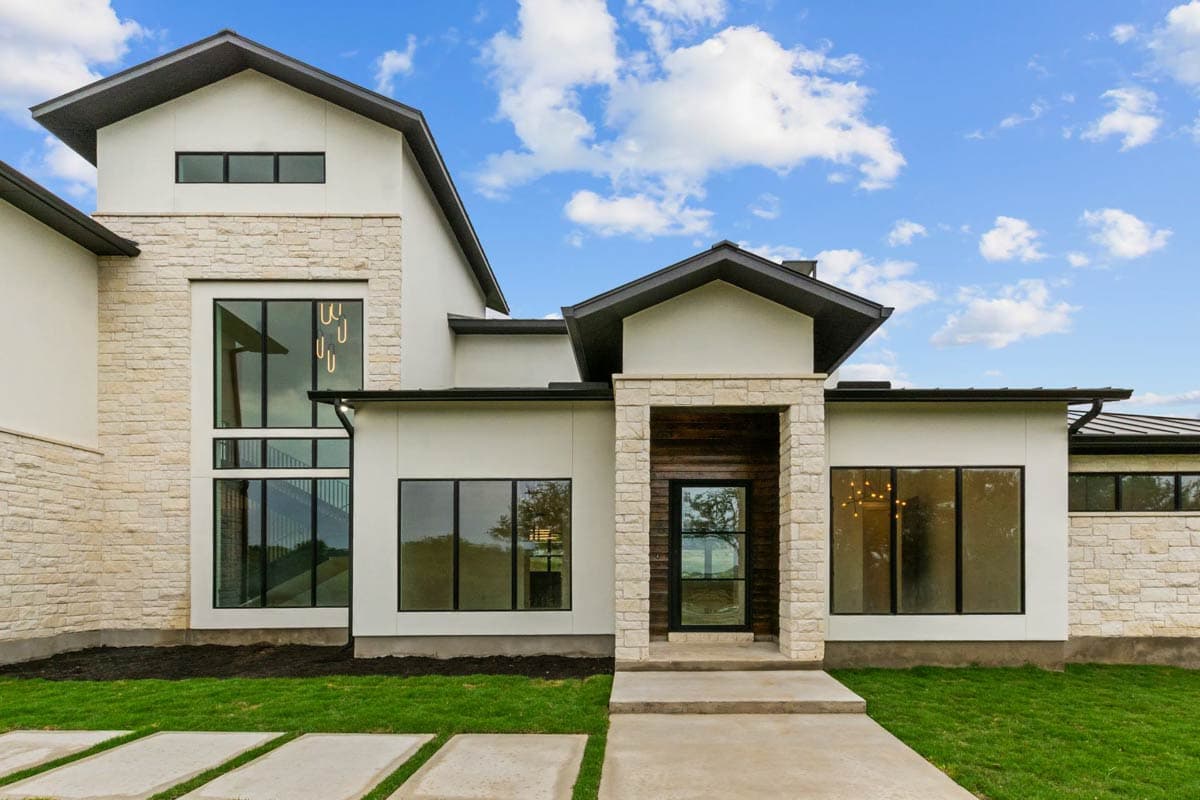 Modern house plan exterior with stone accents, a covered entry, and tall multi-pane windows.