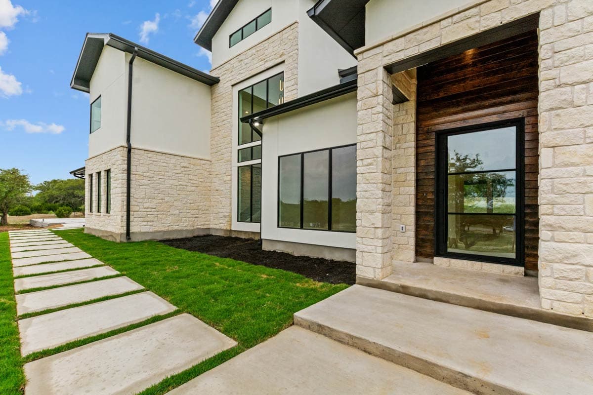Modern house plan exterior with stone and stucco, large windows, and covered entryway with wood paneling.