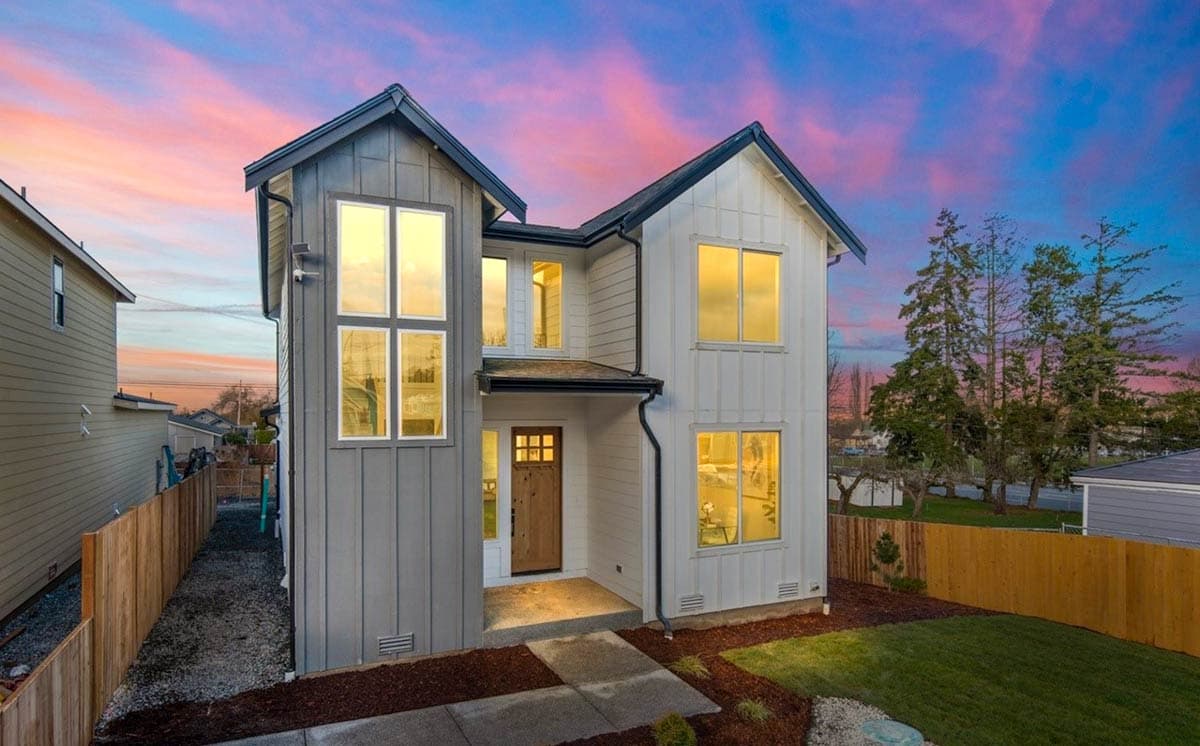 Modern two-story house plan exterior with vertical siding, large windows, and a prominent gabled roof.
