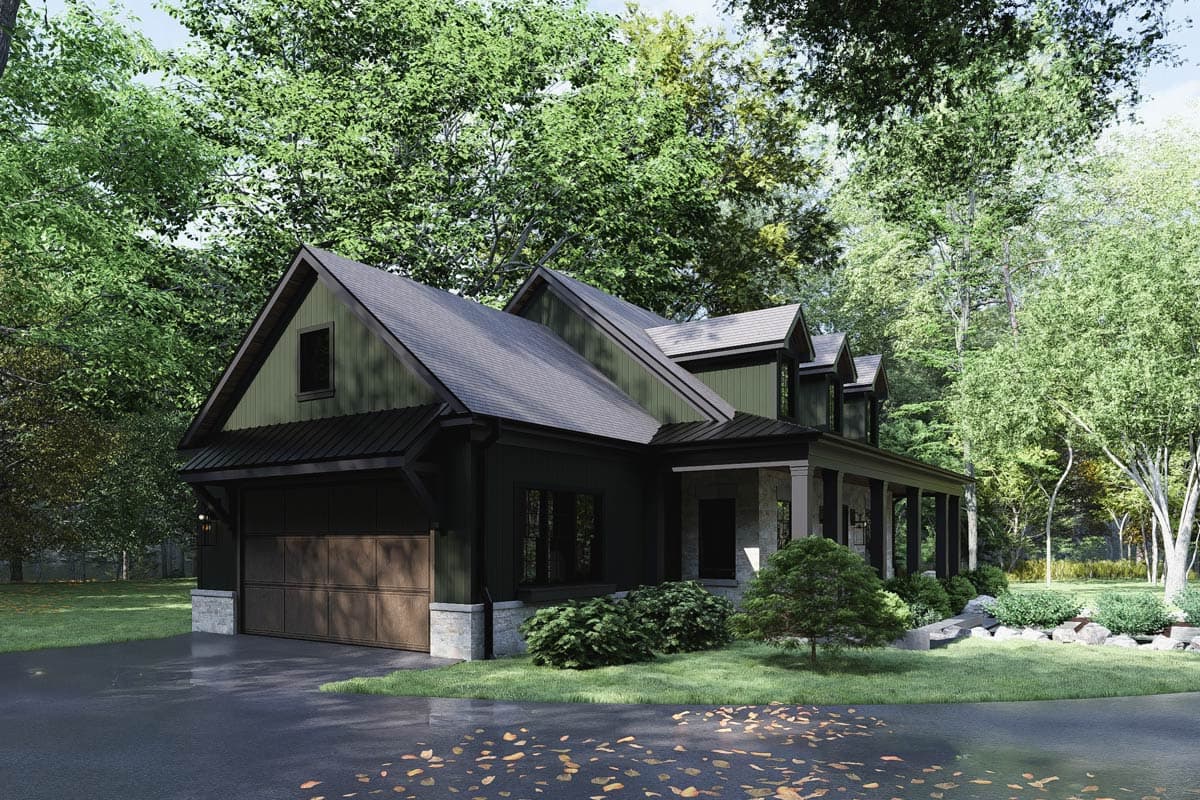 A modern dark green house with a garage and porch set amongst lush trees, on a paved driveway.