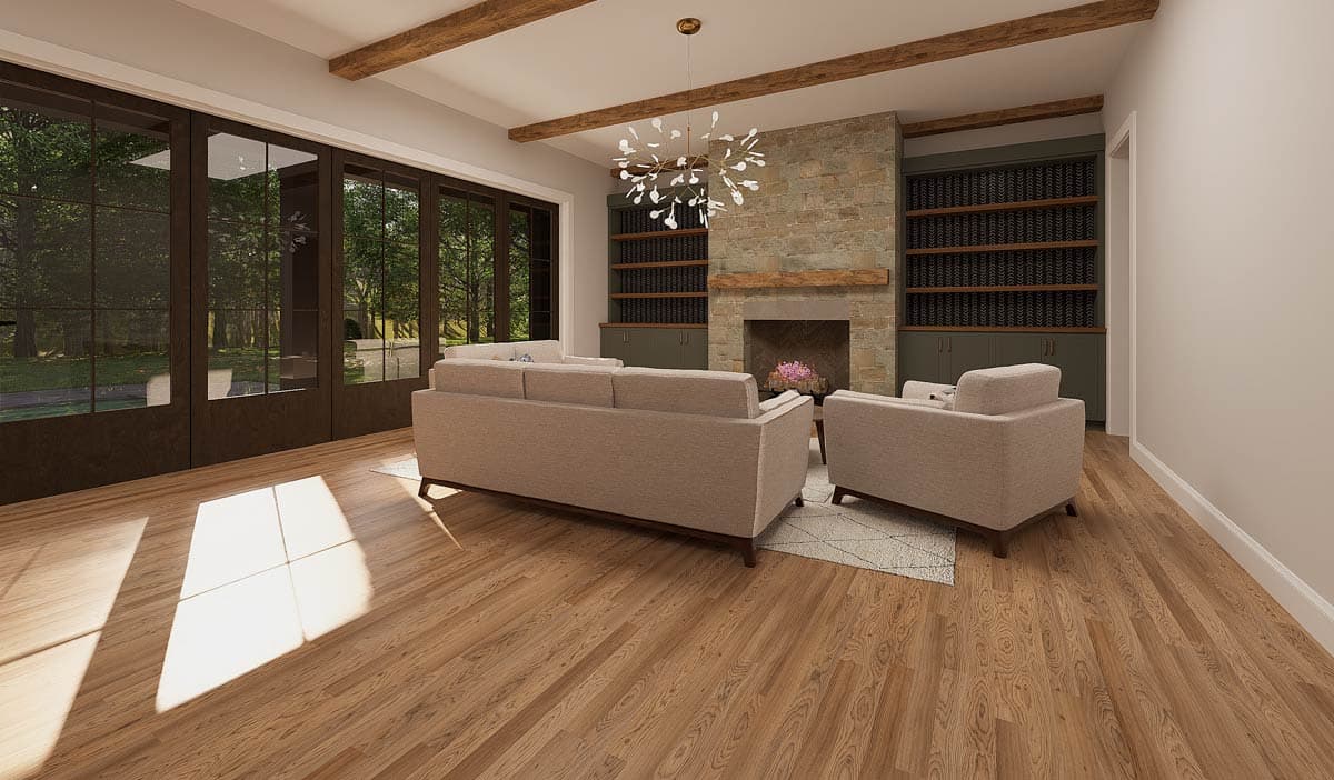 A modern living room with a stone fireplace, built-in shelves, and a large window overlooking a lush green yard.