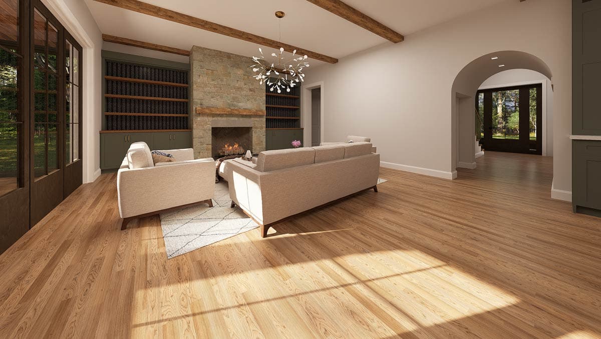 Living room featuring a fireplace with stone surround, two couches, and built-in bookshelves. Natural light streams across the wood floors.