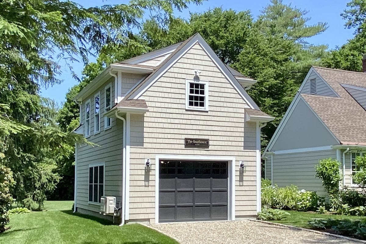 House plan exterior. Two-story structure with gable roof. Includes a garage with carriage-style door, multiple windows, and exterior sconces.