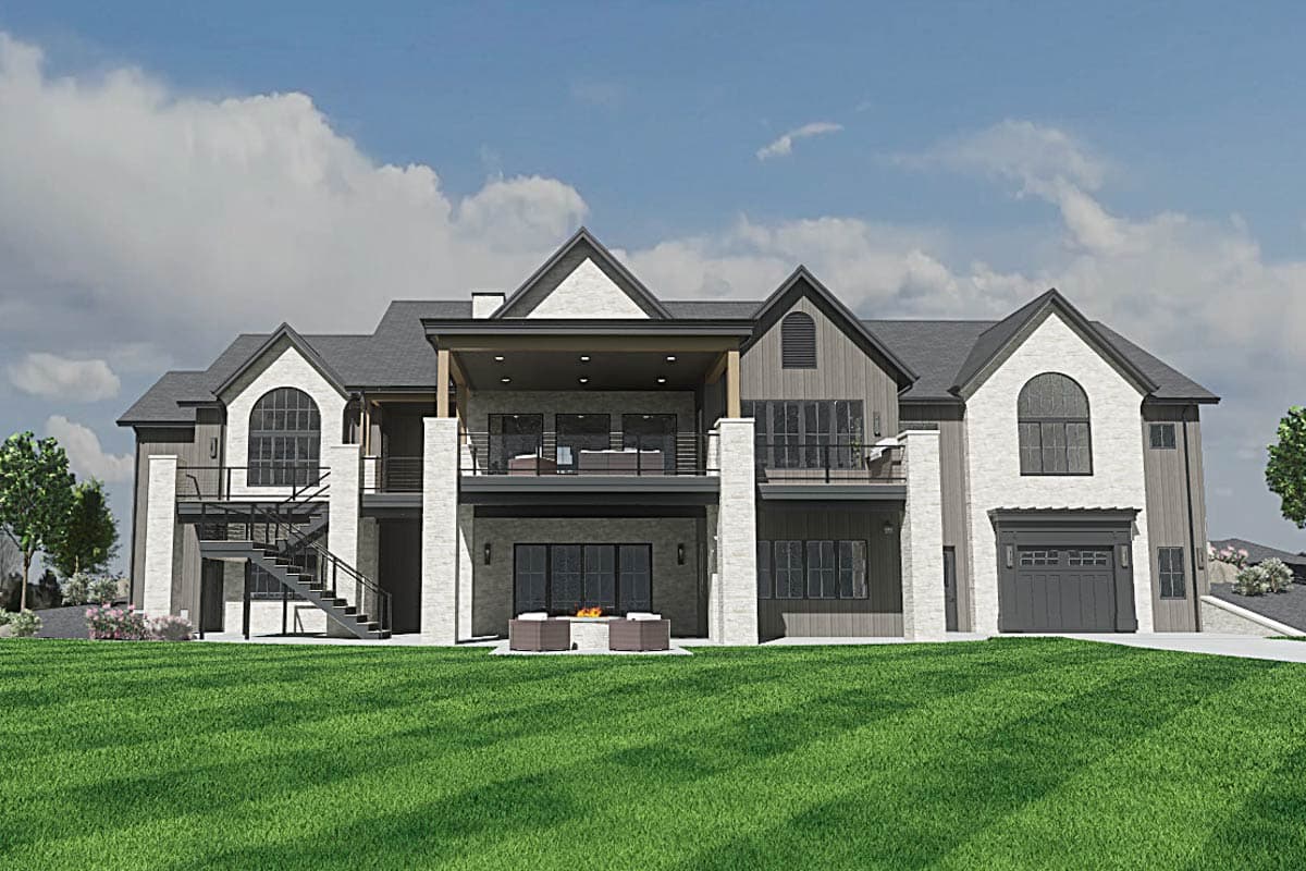 A modern, multi-story home with gray and white brick exterior. The house features multiple balconies and a covered patio with a fireplace and lawn.