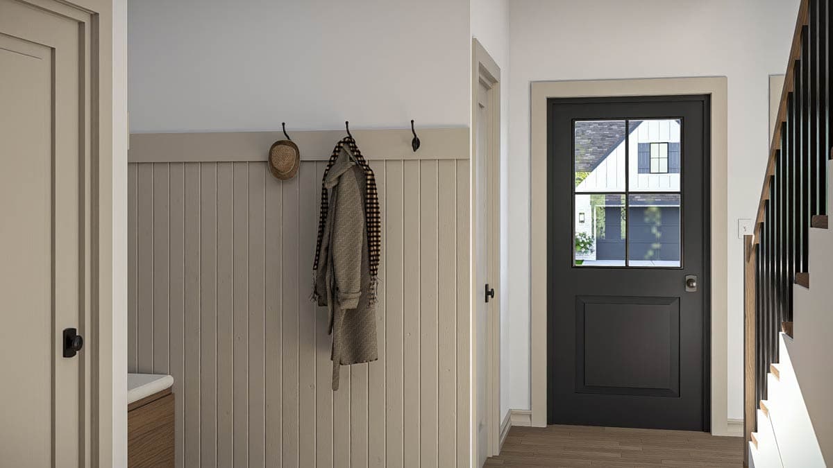 Interior entryway with paneled walls, coat hooks, a dark-paned door, and a staircase with black spindles.