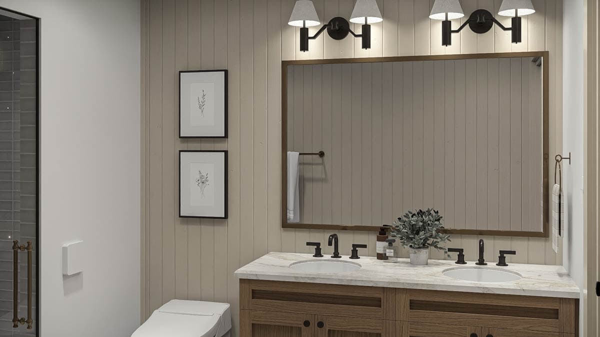 Bathroom vanity with dual sinks, marble countertop, wood cabinetry, and framed mirror with wall sconces.