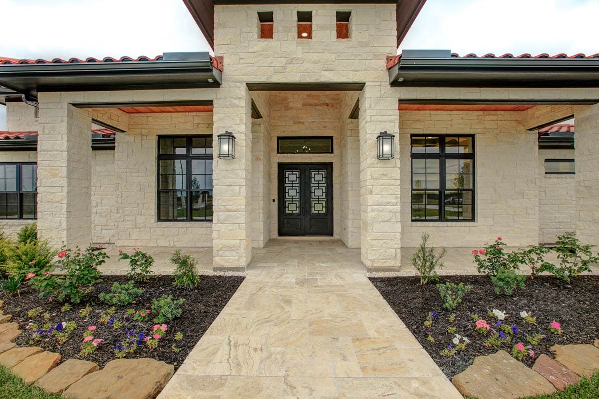 House plan exterior with light stone facade, double entry doors, covered portico, and tile roof.