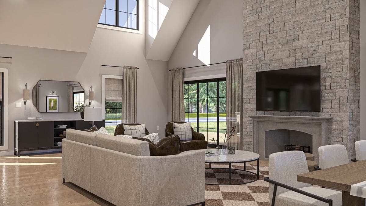Living room with vaulted ceiling, stone fireplace, large windows, and neutral-toned furniture.