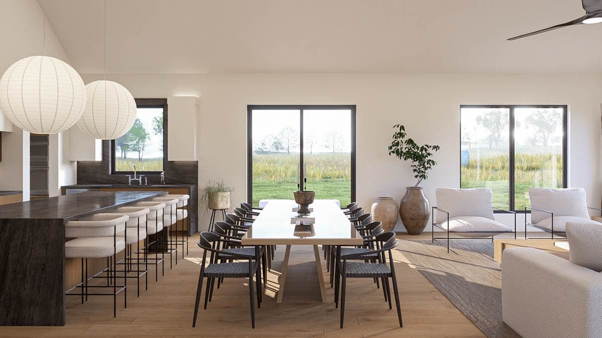 Open concept dining area with large table and island seating, adjacent to a great room with minimalist seating.