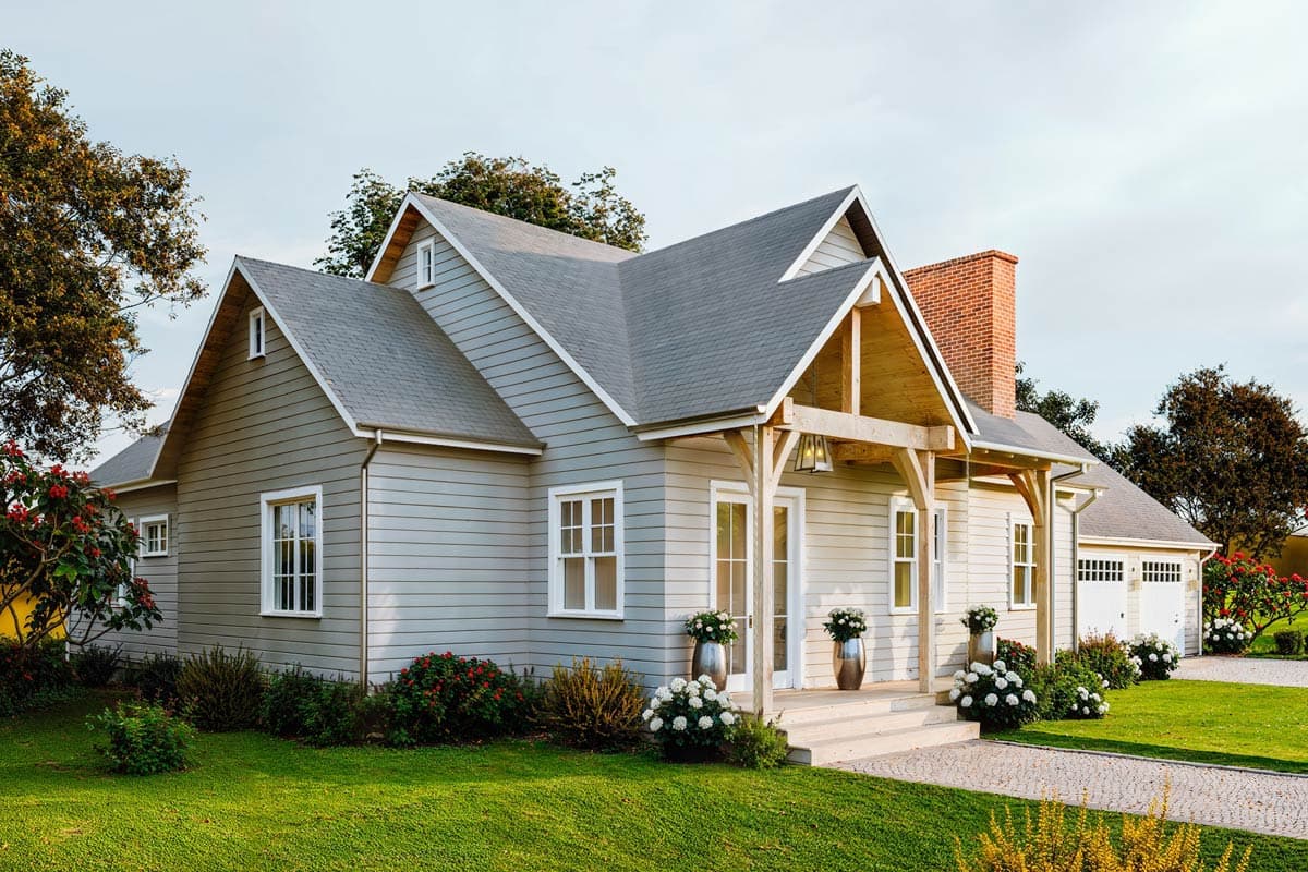 House plan exterior: Modern farmhouse style, 1.5 stories, prominent gabled dormer, exposed rafter tails, and attached two-car garage.