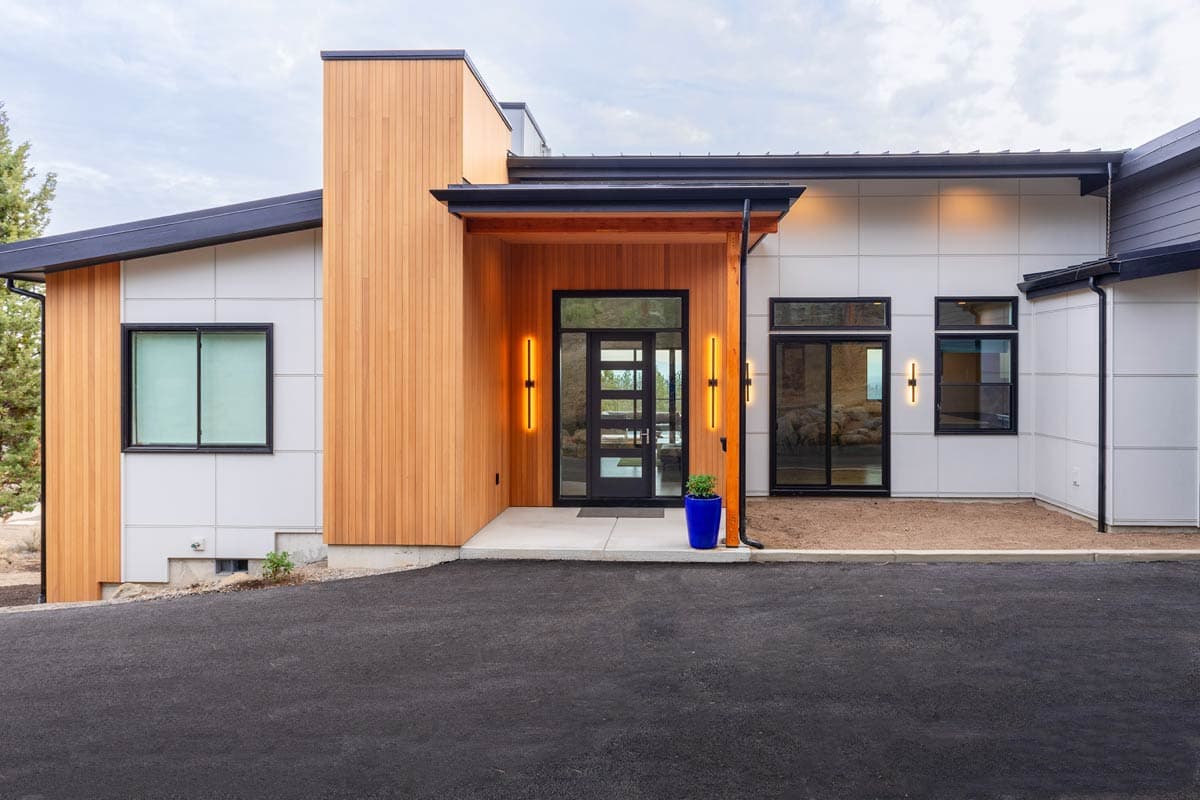 Modern house plan exterior with wood siding, white panels, black-framed windows, and a covered entryway with glass doors.