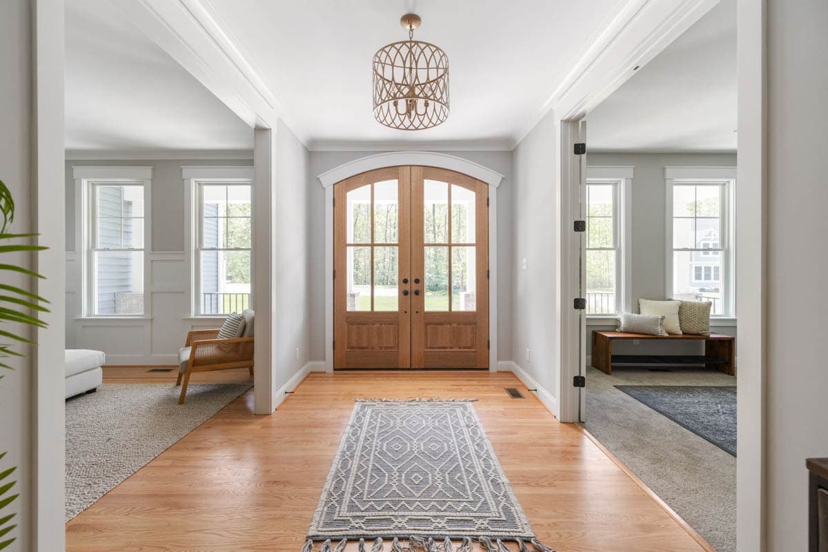 Interior view of a house entryway featuring arched double doors, hardwood floors, and a decorative light fixture.