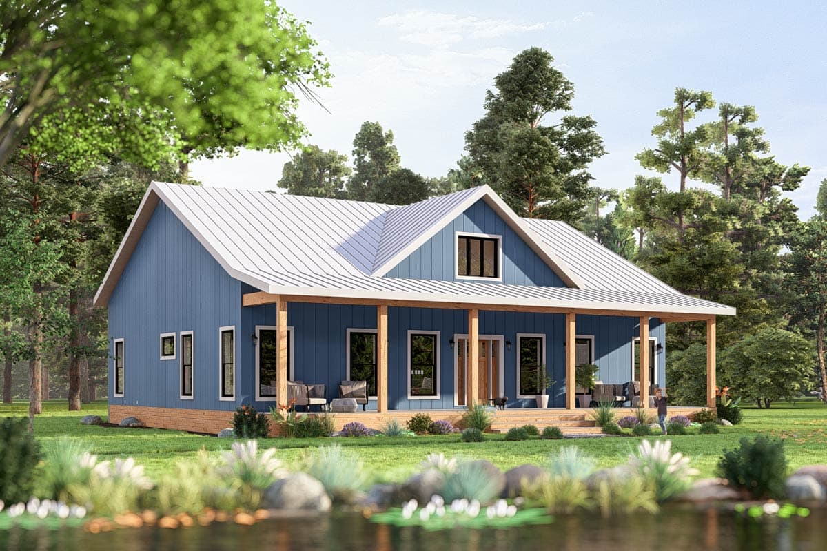 A blue farmhouse with a white roof and wraparound porch set amidst a green lawn and trees. A person stands on the lawn near the porch.