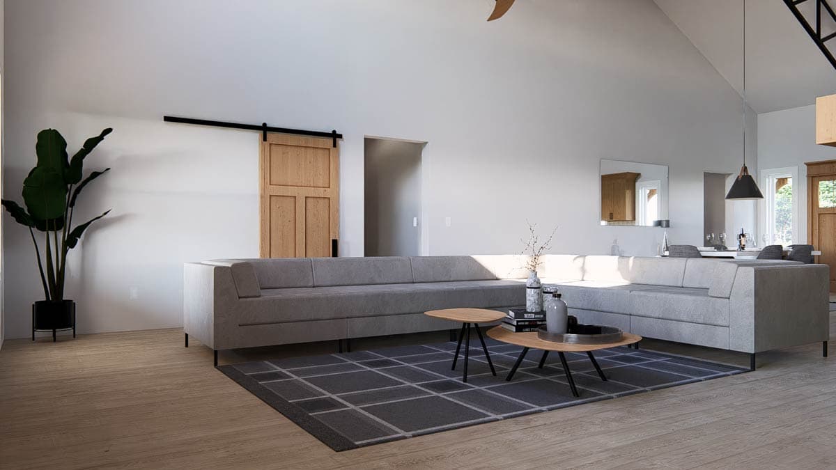 Interior view of a living room with vaulted ceiling, sectional sofa, wooden barn door, and pendant lighting.