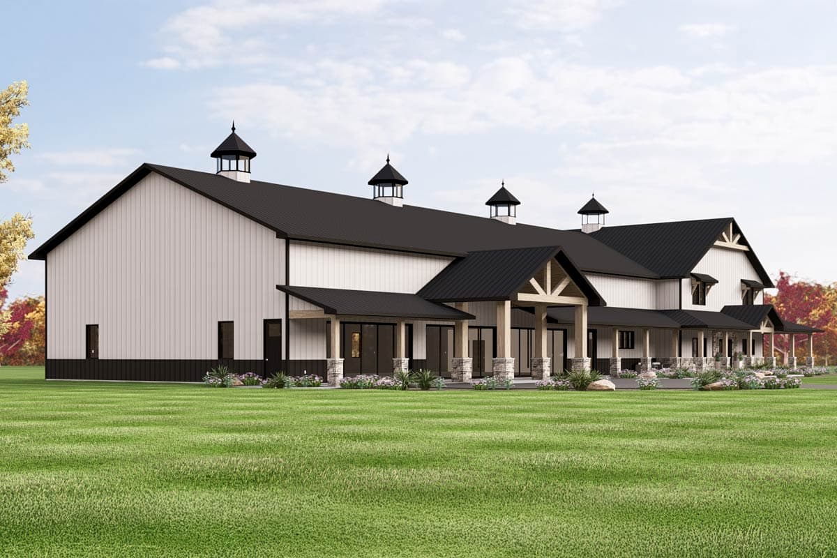 Modern barn-style house plan exterior with a metal roof, cupolas, covered porch with stone columns, and large windows.