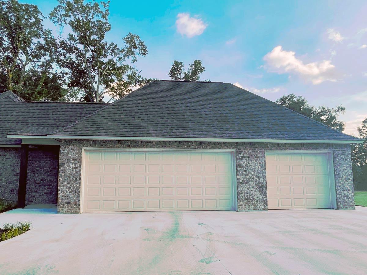 House plan exterior featuring a three-car garage with brick accent walls and a dark shingle roof.