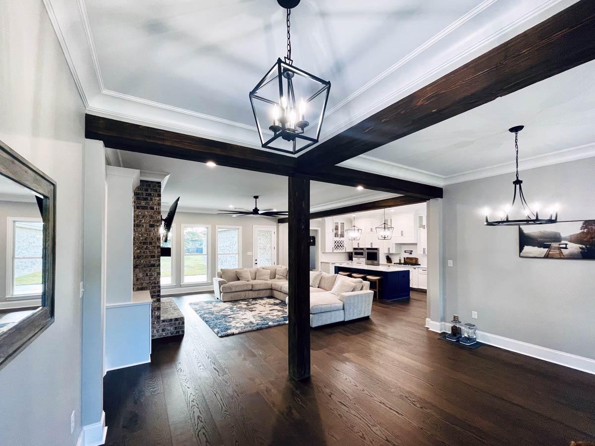 Interior view showing a great room and kitchen with dark wood beams, fireplace, island, and sectional sofa.