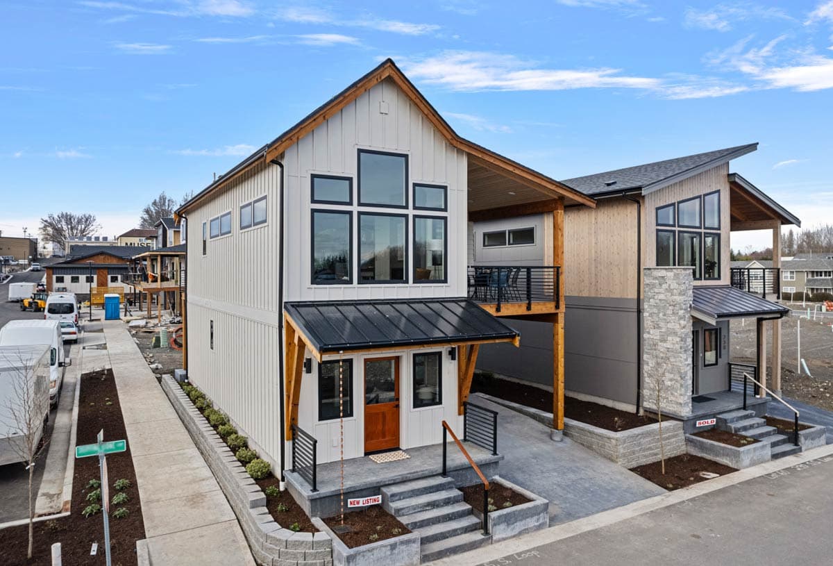 Modern house plan exterior with vertical siding, large geometric windows, metal roof porch, and second-story balcony.