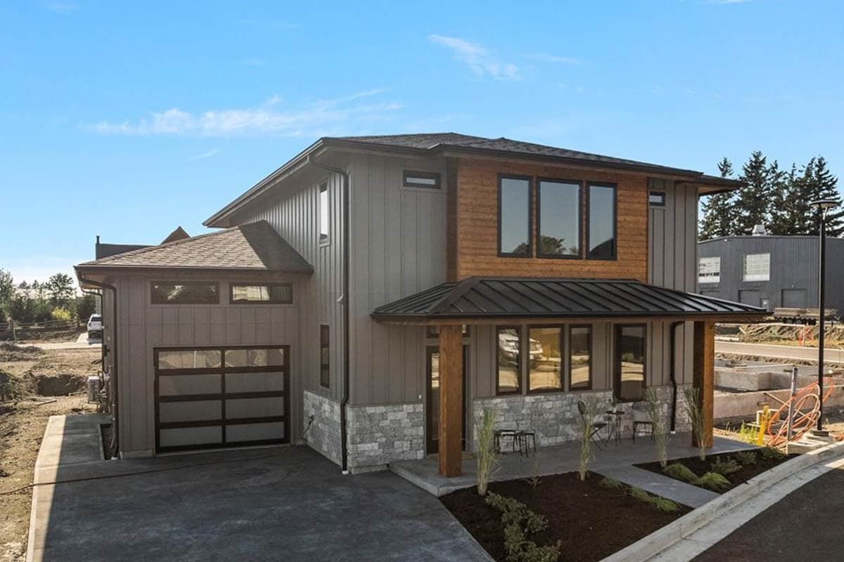 House plan exterior. Two-story Modern house with a porch, shed roof, and attached garage. Exterior features wood siding and stone accents.