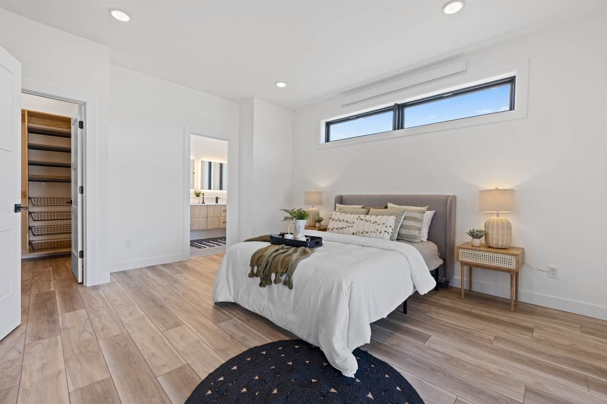 Bedroom with king bed, walk-in closet, and en suite bathroom. Features horizontal windows and wood plank flooring.