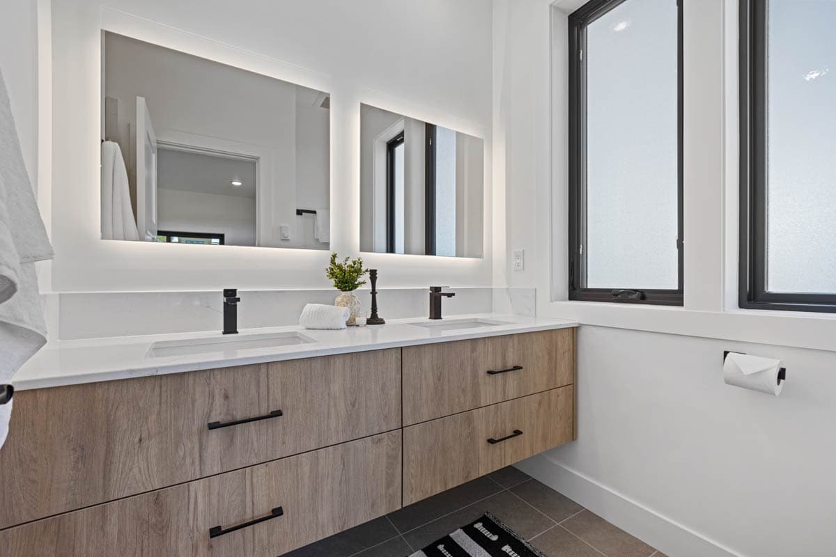 Modern bathroom with a floating wood vanity, dual sinks, lighted mirrors, and large casement windows.