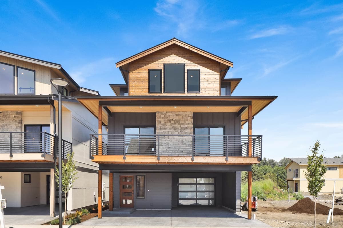 House plan exterior. Two-story Modern house with balcony, wood siding, stone accents, and glass garage door. Features flat rooflines.