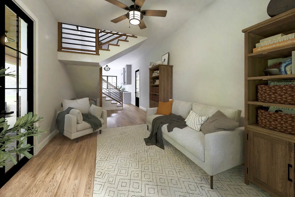 Living room with sofa, armchair, and staircase featuring open risers and metal railings. Wood floor and ceiling fan.