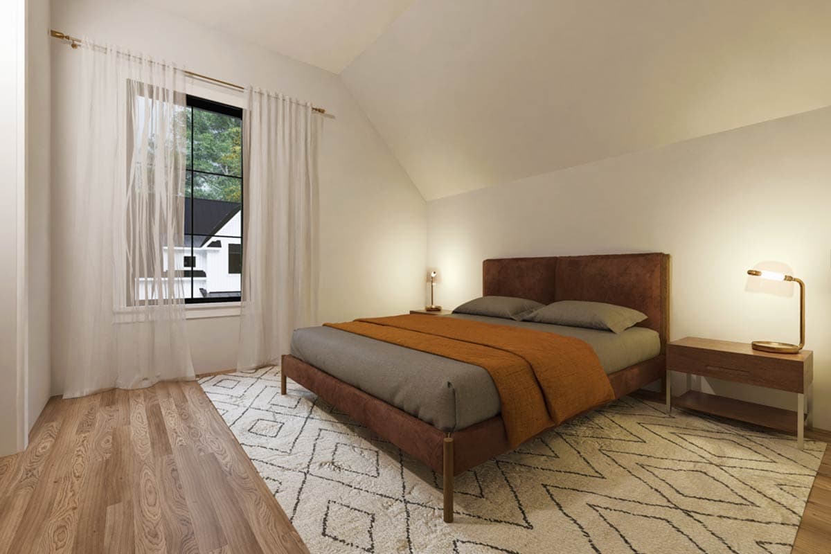 Bedroom with sloped ceiling, large window, brown bed, nightstand, and patterned rug.
