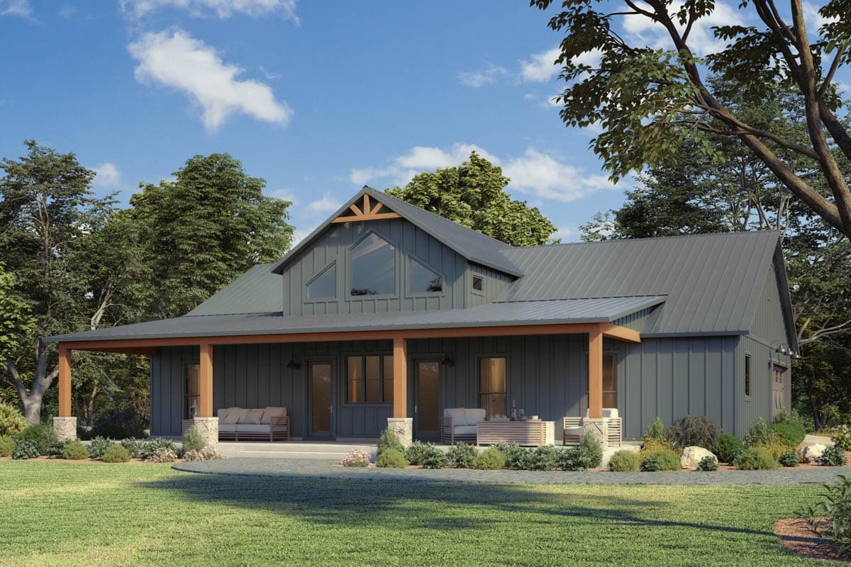 Modern farmhouse with grey siding, metal roof, and large porch. Set in a grassy yard with trees and a blue sky.