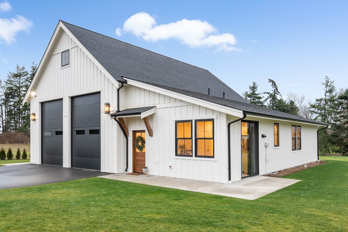 House plan exterior. Modern Farmhouse style with two-story gabled garage, board-and-batten siding, and a shed-roof entry porch.