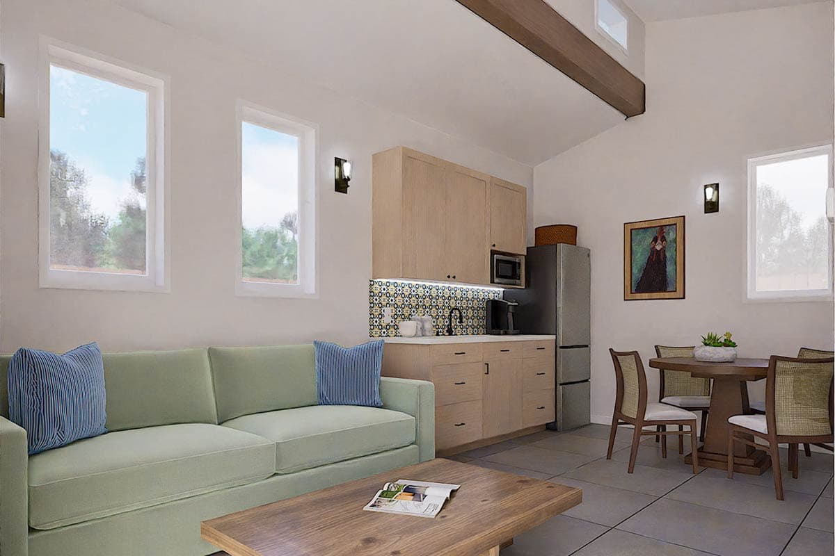 A modern living space features a pale green sofa, wooden cabinetry with a tiled backsplash, and a dining area with a round table.
