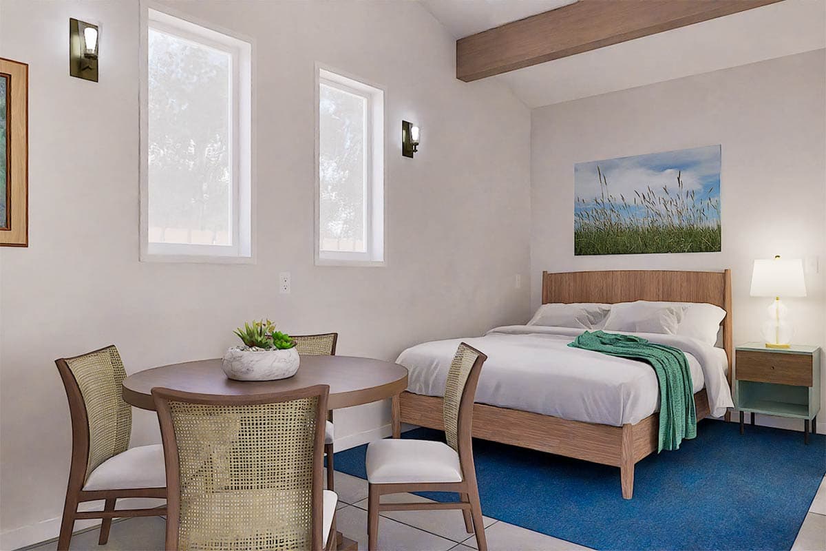 Bright bedroom with a round dining table and four chairs, plus a bed with a wooden frame and a blue rug on the floor.