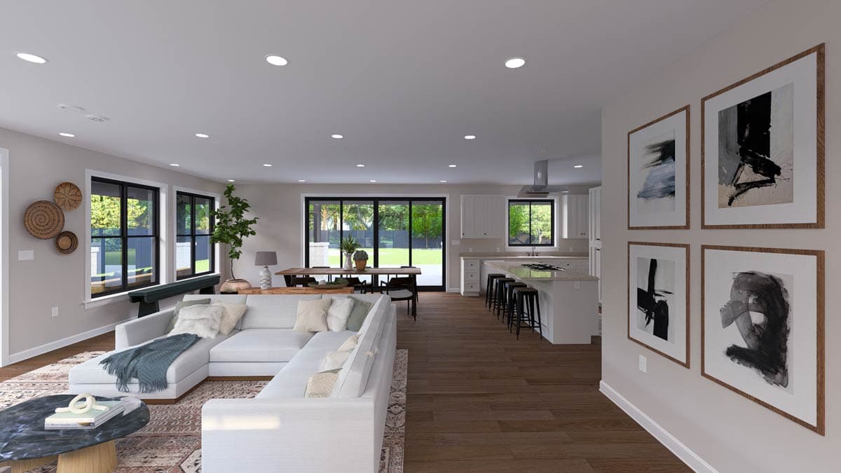Open-concept living area with sectional sofa, dining table, and kitchen island with bar stools. Large windows and sliding glass doors.