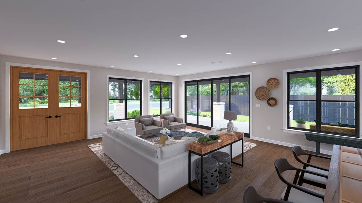 Interior view of a great room featuring double wood doors, large windows, and an L-shaped sectional sofa.