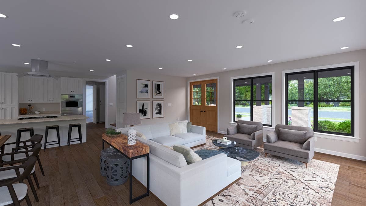 Open concept living space with kitchen island, sectional sofa, fireplace, and large windows.