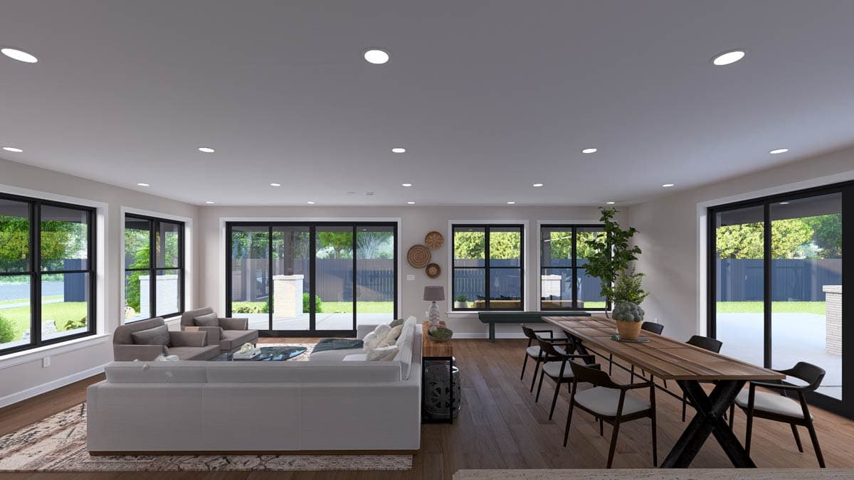 Open-concept living and dining area with large windows, sectional sofa, and wooden dining table.
