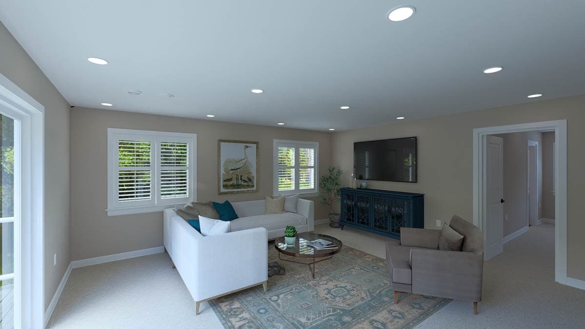 Living room with sectional sofa, armchair, coffee table, media console, and television. White plantation shutters on windows.