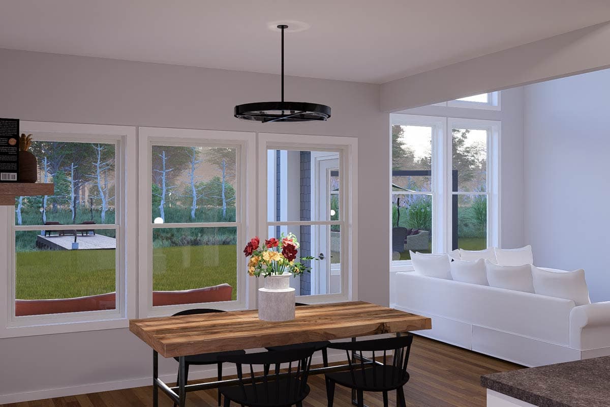 Interior rendering of an open-concept living space with dining table, large windows overlooking a yard and trees, and a white sofa.